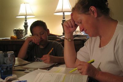 Woman and son, both doing homework on a table
