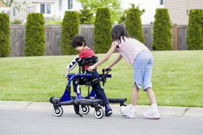 Girl helping her younger brother walk in an apparatus