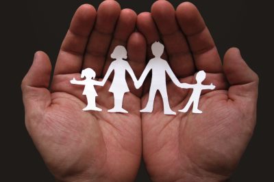 A pair of hands holding a cut out family