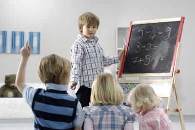 Young child at a blackboard teaching three other childeren