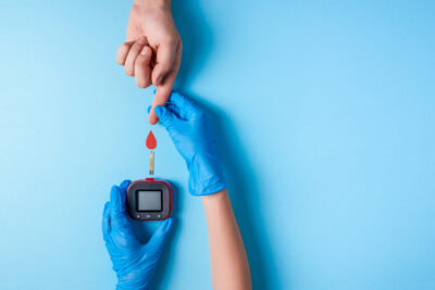 Nurse making a blood test. . Man's hand with red blood drop with Blood glucose test strip and Glucose meter. Copy space. Top view